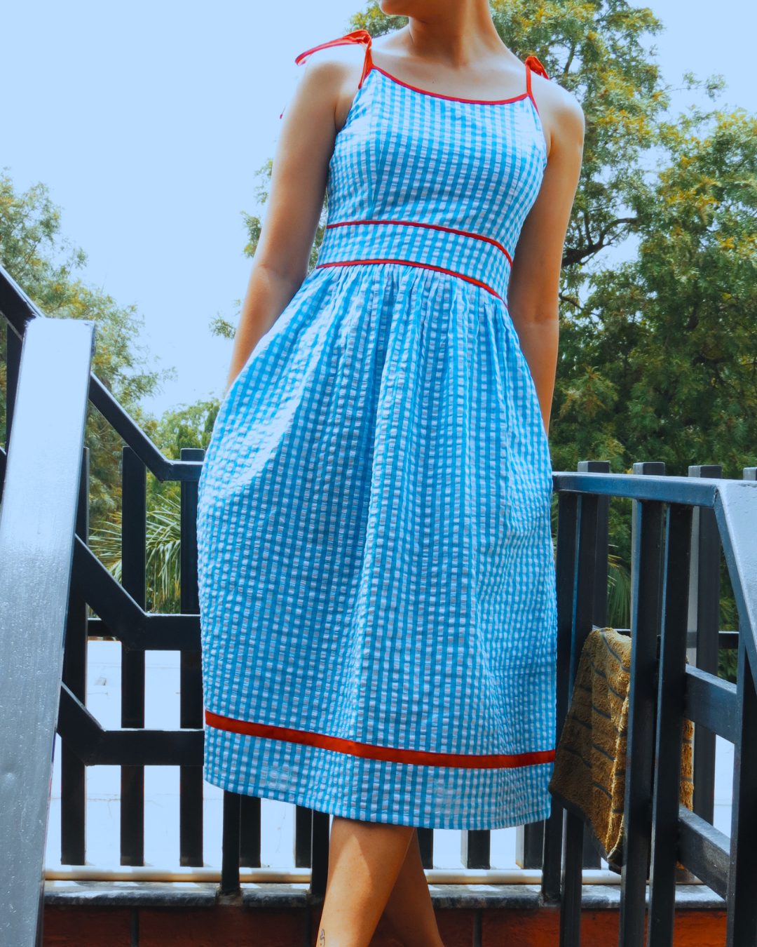 Woman in the blue gingham Aasmani dress outdoors on a stairway
